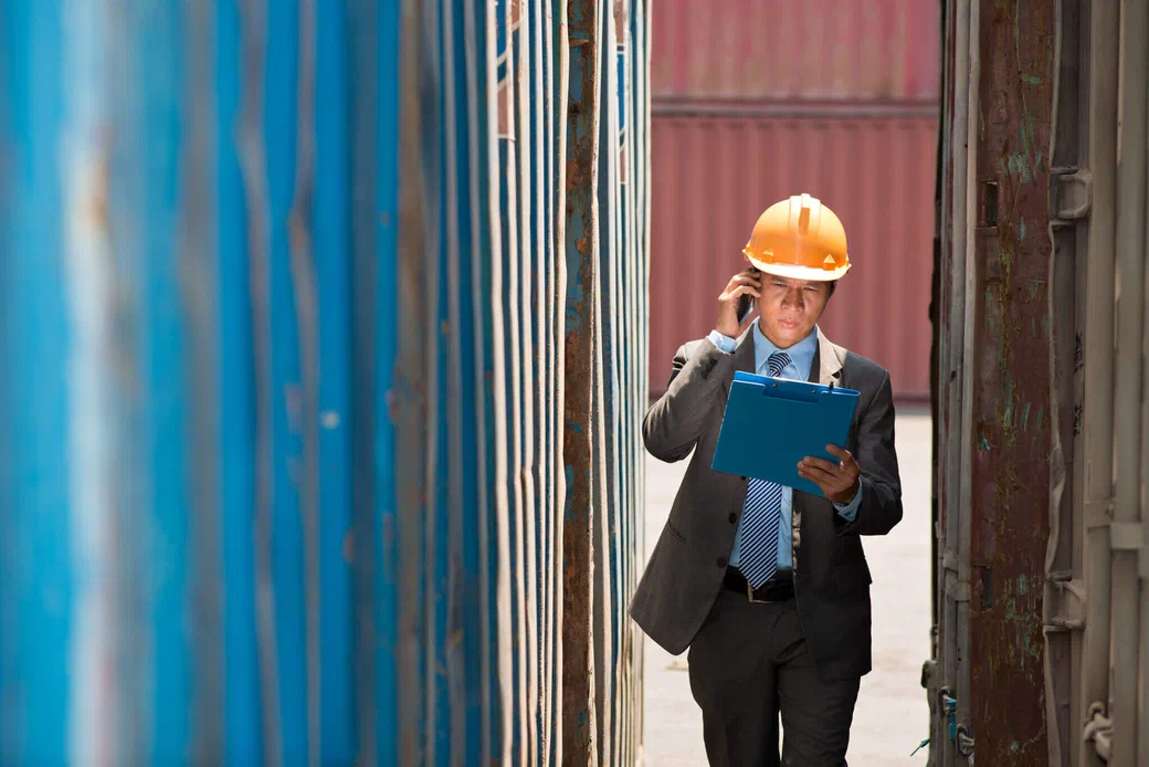 An inspector reviewing cargo at a busy port