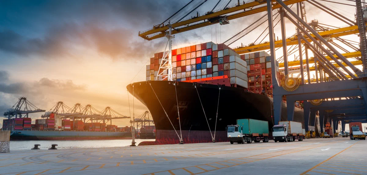 A container ship being loaded by ship-to-shore cranes at sunset